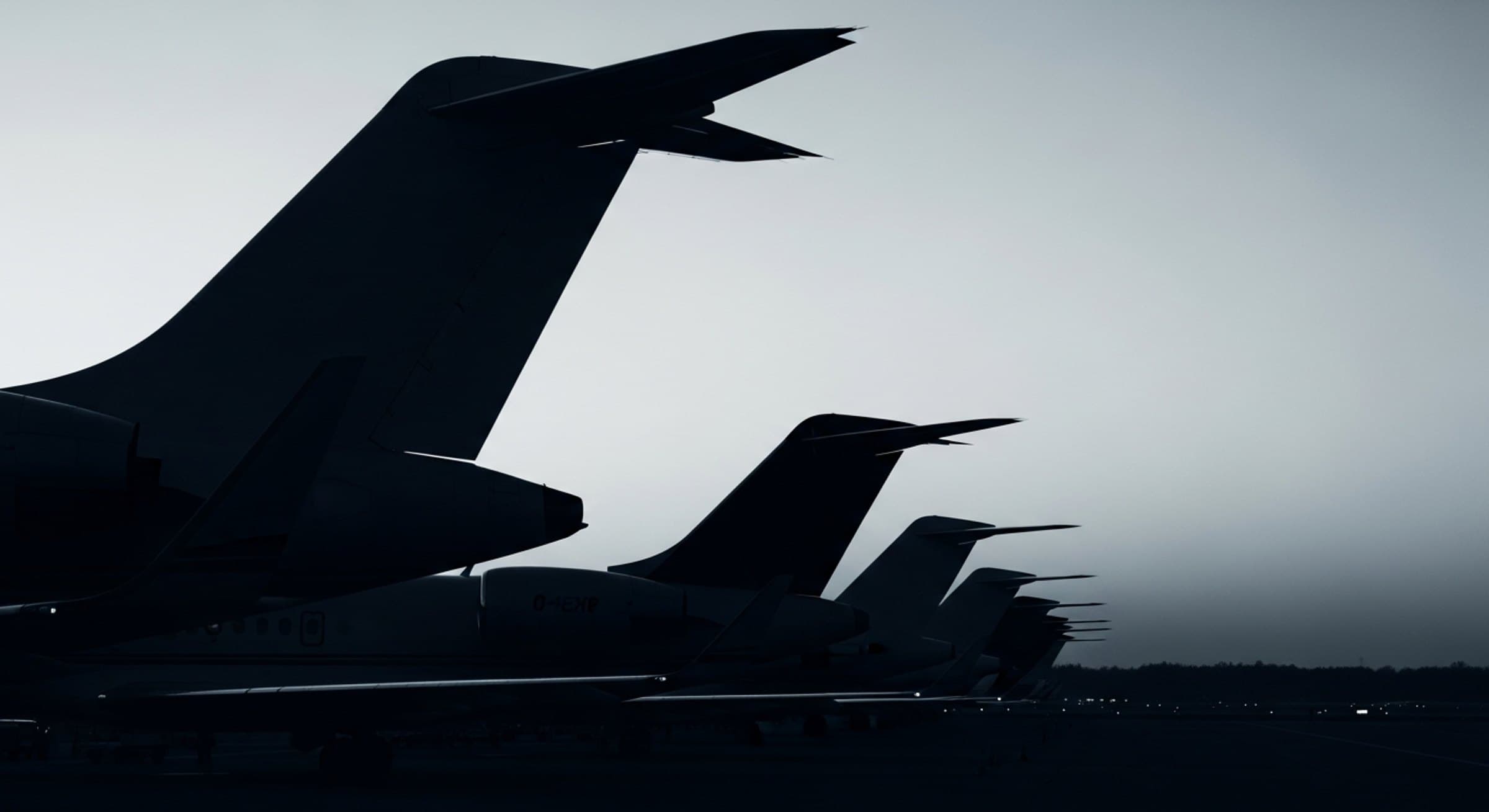 Row of business jet tail fins on a ramp at dusk